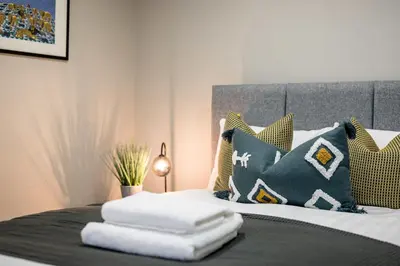 a bed with a bunch of pillows on it at Picasso's Place Liverpool Apt Sleeps 9 in Liverpool