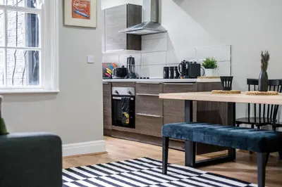 a kitchen with a table and chairs in a room at Picasso's Place Liverpool Apt Sleeps 9 in Liverpool