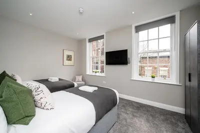 a bedroom with two beds and a tv on the wall at Lennon's Place Central Apartment Sleeps 5! in Liverpool