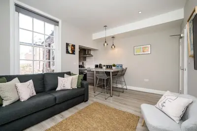 a living room with a couch and a kitchen at Lennon's Place Central Apartment Sleeps 5! in Liverpool