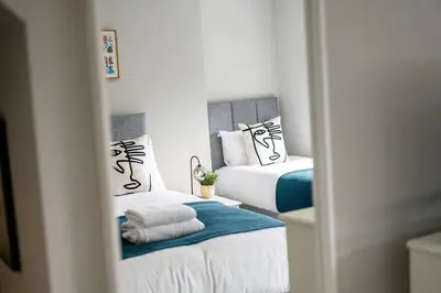 a bedroom with two beds with white and blue at Attico, 2BR City Centre Apartment, Sleeps 6! in Liverpool