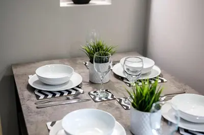 a table with white plates and glasses and plants at Attico, 2BR City Centre Apartment, Sleeps 6! in Liverpool