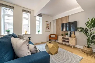 a living room with a blue couch and a tv at Liverpool City Centre Apartment in Liverpool