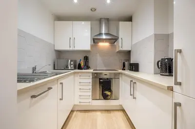 a kitchen with white cabinets and a dishwasher at Liverpool City Centre Apartment in Liverpool