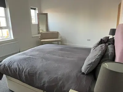 a bedroom with a bed and a chair at Chestnut House in Southport