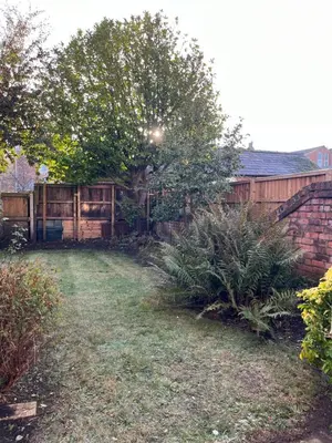 a backyard with a tree and a brick wall at Chestnut House in Southport