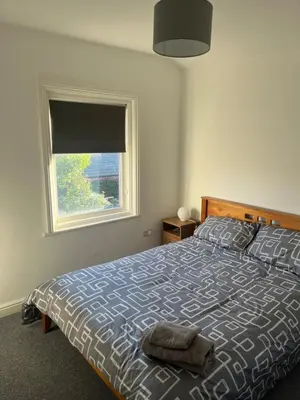 a bedroom with a large bed with a window at Chestnut House in Southport