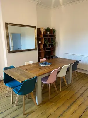 a dining room table with chairs and a mirror at Chestnut House in Southport