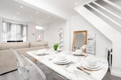 a white living room with a table and a couch at Beautiful House - Free Parking - 5 mins to centre in Liverpool