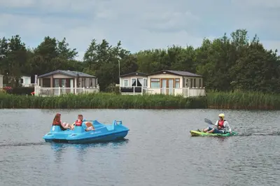 two people are riding on an inflatable boat in the water at Miarlo Lodge Derwent Haven Lakeland in Grange Over Sands