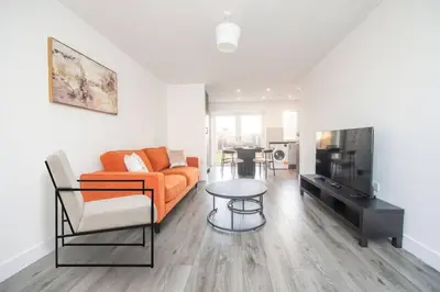 a living room with an orange couch and a table at Brand-New 3-Bed Home - Liverpool in Liverpool