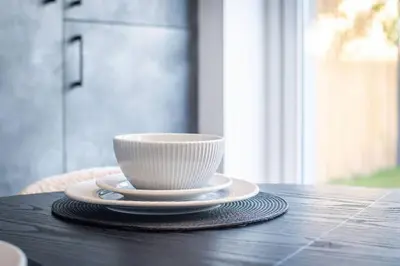 a white cup and saucer on a wooden table at Brand-New 3-Bed Home - Liverpool in Liverpool