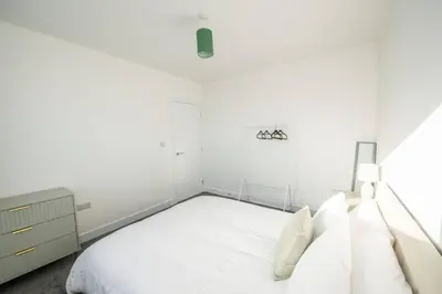 a white bedroom with a bed and a dresser at Brand-New 3-Bed Home - Liverpool in Liverpool