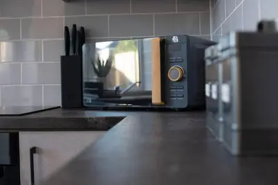 a black microwave sitting on a counter in a kitchen at Brand-New 3-Bed Home - Liverpool in Liverpool