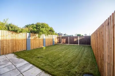 a backyard with a fence and a yard withgrass at Brand-New 3-Bed Home - Liverpool in Liverpool