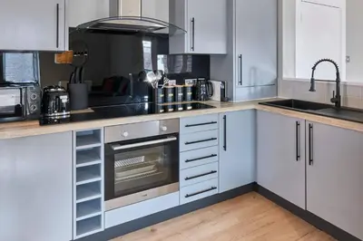 a kitchen with white cabinets and a sink and a stove at Ropewalks Retreat III - Sleeping 8 Guests with Parking in Liverpool