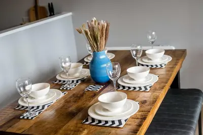 a wooden table with plates and cups and wine glasses at Ropewalks Retreat IV Sleeping 6 Guests with Parking and Balcony in Liverpool