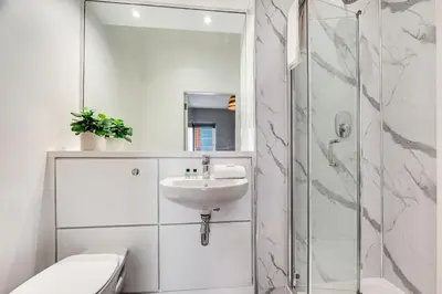 a white bathroom with a sink and a shower at Ropewalks Retreat IV Sleeping 6 Guests with Parking and Balcony in Liverpool