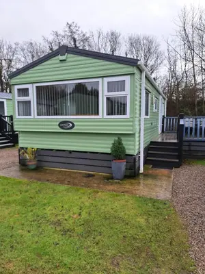 a green tiny house sitting on a wooden deck at 11 Borwick Lakes in Carnforth