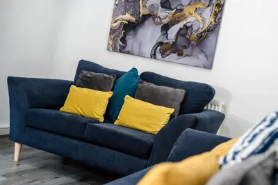 a blue couch with yellow pillows in a living room at Cameron House - Air Host & Stay - Contractor Friendly in Liverpool