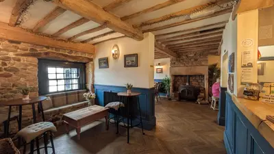 a room with a table and chairs and a fireplace at The Golden Ball Hotel Pods in Torrisholme