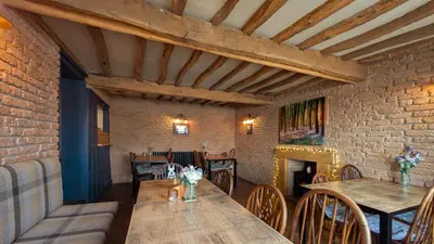 a dining room with a table and a fireplace at The Golden Ball Hotel Pods in Torrisholme