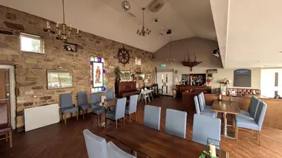 a restaurant with chairs and tables and a stone wall at The Golden Ball Hotel Pods in Torrisholme