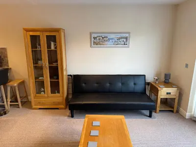a living room with a black couch and a table at Modern, sleeps 5, parking, semi rural, Upholland in Upholland