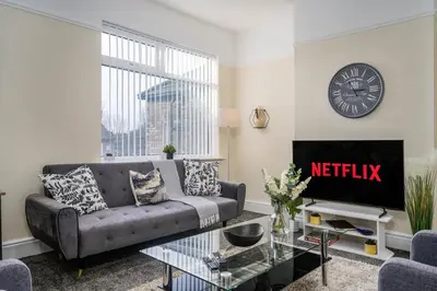 a living room with a couch and a clock on the wall at Liverpool 3 Bedroom Contractor Stay Cherry House in Liverpool