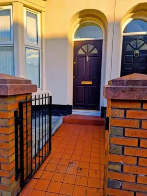 a house with a brown door and a brick fence at Beautiful home near LFC Stadium in Liverpool