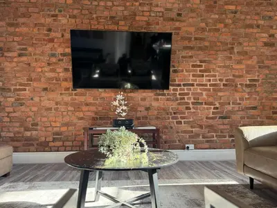 a brick wall with a tv and a table in a room at Stylish city centre Penthouse in Liverpool
