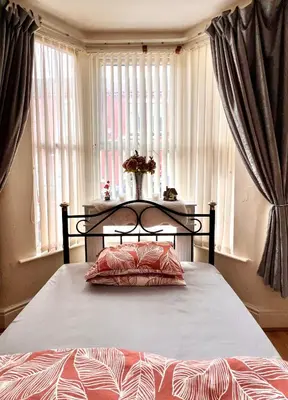 a bed in a bedroom with windows with curtains at Anfield Goodison Stanley Park Liverpool in Liverpool