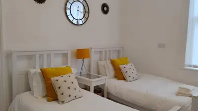 two beds in a room with a clock on the wall at Charming six bedroom townhouse citystay close to city centre in Liverpool