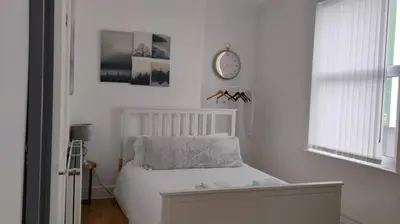 a white bedroom with a bed and a clock on the wall at Charming six bedroom townhouse citystay close to city centre in Liverpool