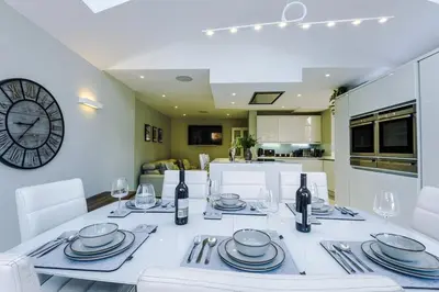 a dining room with a white table and a clock at Home in Preston 4 beds FAST WIFI in Samlesbury