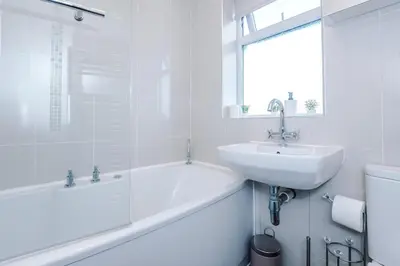 a white bathroom with a sink and a bath tub and a sink at Home in Preston 4 beds FAST WIFI in Samlesbury