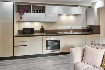 a kitchen with white cabinets and a sink and a couch at Host & Stay - Chic Townhouse by the Docks in Liverpool
