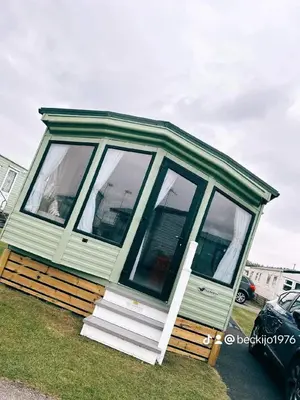a green tiny house sitting on the grass at Metcalfes family caravan in Heysham