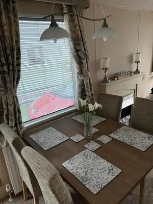a dining room table with a vase of flowers on it at Metcalfes family caravan in Heysham