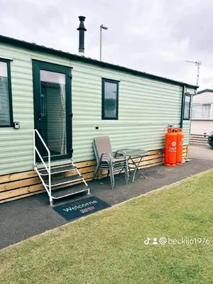 a house with two chairs and a table in front of it at Metcalfes family caravan in Heysham