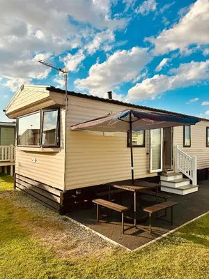 a mobile home with a picnic table and a bench at Ocean Pearl Home in Heysham