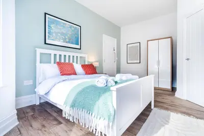 a bedroom with a white bed with red pillows at 5 Bedroom House All En-Suite Ideal for Contractor Stays in Wallasey