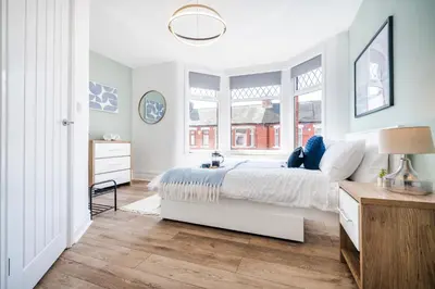 a white bedroom with a bed and two windows at 5 Bedroom House All En-Suite Ideal for Contractor Stays in Wallasey