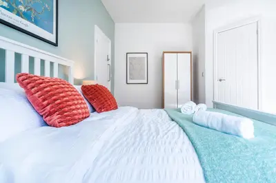 a bedroom with a large white bed with red pillows at 5 Bedroom House All En-Suite Ideal for Contractor Stays in Wallasey