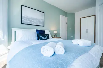 a bedroom with a large bed with towels on it at 5 Bedroom House All En-Suite Ideal for Contractor Stays in Wallasey