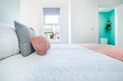 a bedroom with a bed with pillows and a window at 5 Bedroom House All En-Suite Ideal for Contractor Stays in Wallasey
