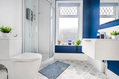 a bathroom with a shower and a toilet and blue walls at 5 Bedroom House All En-Suite Ideal for Contractor Stays in Wallasey