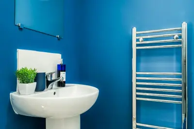 a bathroom with a white sink and a blue wall at 5 Bedroom House All En-Suite Ideal for Contractor Stays in Wallasey