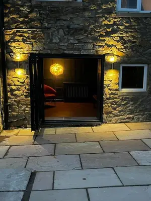 a stone building with a door open to a patio at Weavers Cottage Whalley in Whalley