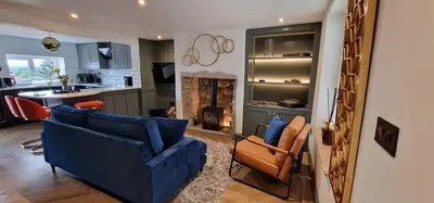 a living room with two blue couches and a kitchen at Weavers Cottage Whalley in Whalley